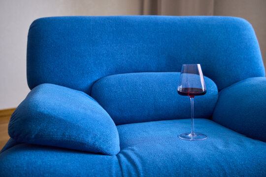 A mishap occurred where red wine was spilled on a vibrant blue couch during a celebration event