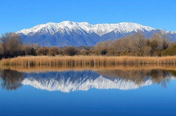 A snow-capped mountain range reflected in a calm lake,