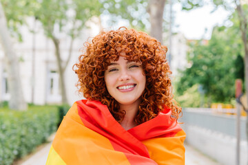 Curly-haired redhead standing proudly, embracing rainbow flag, symbolizing lgbtq+ solidarity and...