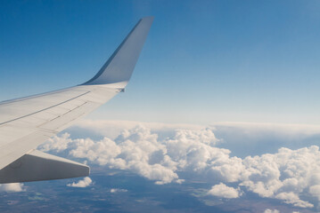 view from airplane on wing in sky with beautiful clouds at altitude in flight