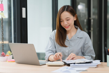 Young Woman Working with Calculator and Laptop