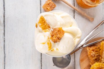 Custard base Milk and honey ice cream, sweet summer frozen dessert, bowl of creamy homemade honey taste gelato with honeycomb topping and honey drizzles