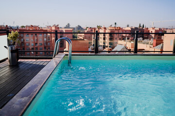 A serene rooftop pool reflecting sunlight amid a vibrant cityscape, offering a tranquil retreat in an urban environment in Marrakesh hotel
