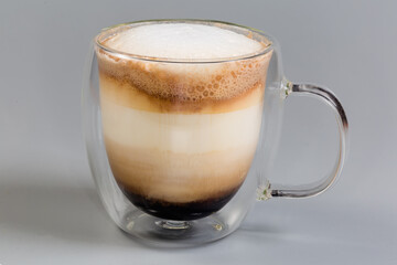 Cappuccino in glass double-walled hollow cup on gray background