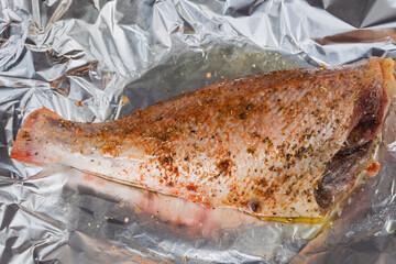Raw redfish carcass marinated in spices on foil sheet