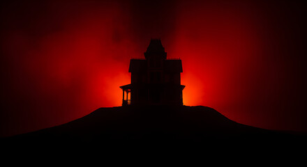 Obraz premium Silhouette of Dark Victorian Mansion on Hill with an Ominous Red Sky at Twilight