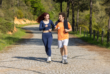 Obraz premium Happy and athletic young couple running in the forest.