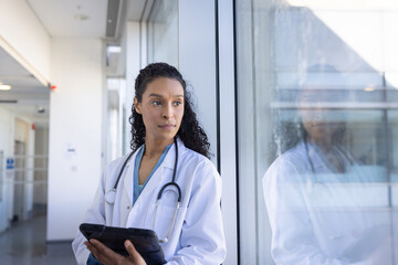 Focused doctor with tablet in hospital hallway
