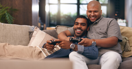 Home, gay couple and gaming with controller on sofa for multiplayer, competition and entertainment. Lgbtq, queer love and men with smile in living room for esports challenge, streaming and contest © peopleimages.com