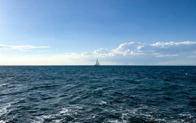 lonely sailboat on the deep blue open sea under calm sky. minimalist travel concept with empty space and emotional atmosphere