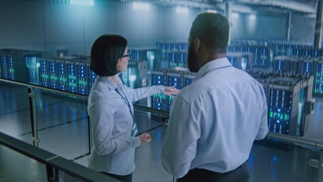 Big Data Center Multiethnic Specialists with Digital Tablet Talking, Shaking Hands, Looking at Camera. Server Racks for Cloud Computing Technology. Concept of Information Digitalization, Web Service.