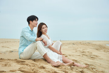 Fototapeta premium Young Man and Woman Sitting Together on Beach