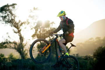 Balance, bike and off road with man in mountains for outdoor adrenaline, adventure or training. Exercise, fitness and wheelie with person cycling in nature for challenge, competition or performance