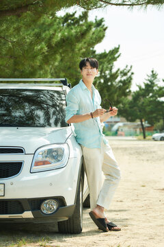 Young Asian Man Leaning on White Car Outdoors