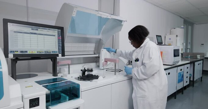 Black African female scientist checking scientific machinery doing medical research in a laboratory
