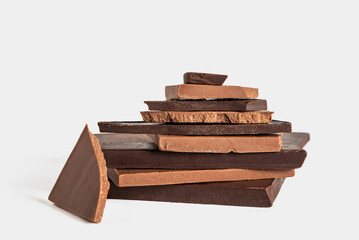 Stack of artisanal dark and milk chocolate bars and pieces, placed on top of each other, white background.