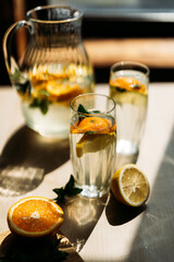 Two chilled glasses of homemade lemonade with vibrant citrus slices and fresh mint on a wooden surface. Perfect for representing summer freshness and wellness.