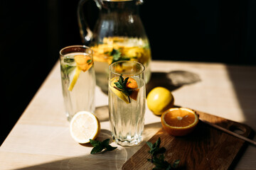 A pitcher of homemade lemonade filled with fresh lemon slices and sprigs of mint, ready to serve. Sunlight enhances the vibrant colors, making it perfect for healthy beverage concepts.