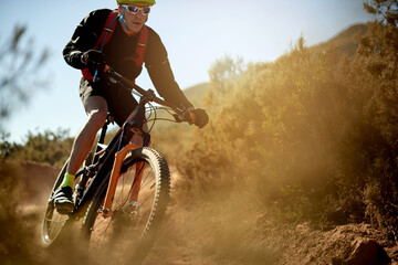 Nature, sports and athlete on dirt road trail for gravel race, challenge or competition training. Fitness, mountain bike and man cyclist riding in mud outdoor for exercise or workout with speed.