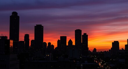 Fototapeta premium City Skyline at Sunrise - Silhouetted cityscape at dawn, vibrant orange and purple sky. Stunning urban panorama