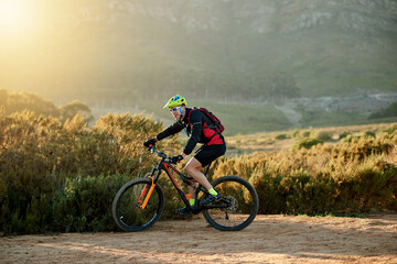 Naklejka premium Man, cyclist and nature with mountain bike for extreme sport, fitness or outdoor exercise. Active, male person or riding in wilderness with bicycle or helmet for cycling or adrenaline on dirt road