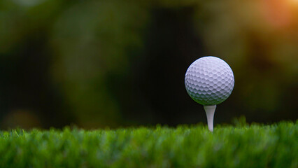 Golf ball on tee in beautiful golf course with sunset.