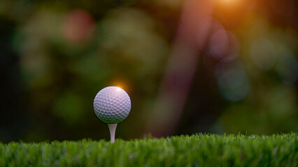 Golf ball on tee in beautiful golf course with sunset.