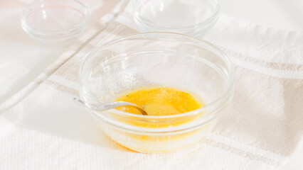 Small glass bowl containing melted butter and seasonings.
