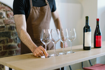 Sommelier preparing wine tasting, arranging empty glasses on table