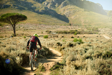 Back, cycling and dirt road with man in mountains for outdoor exercise, fitness or hobby. Scenic, trail riding and view with cyclist on space in nature for challenge, performance or sports training