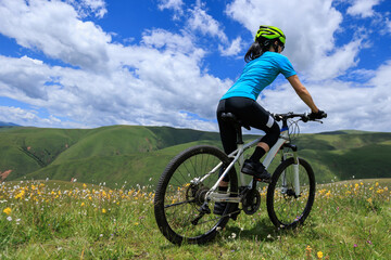 Fototapeta premium Asian woman riding a mountain bike down hill on beautiful mountain top