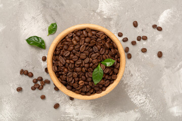 Roasted coffee beans with leaves on concrete background,top view
