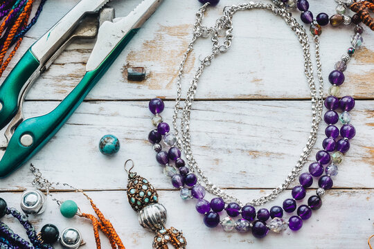 Amethyst gemstone necklace and jewelry making tools on rustic white wood background Free space for text Mockup