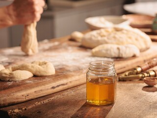 Morning light bathes a rustic kitchen as a baker lovingly drizzles golden honey over freshly baked bread. The honey's vibrant essence fills the air, enhancing this farm-fresh moment