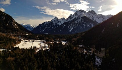Una panorámica panorámica revela un impresionante paisaje antiguo, salpicado de majestuosas montañas nevadas, cuyas cimas brillan bajo la luz del sol. 