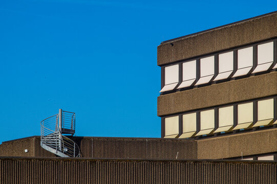 Spiral staircase on a rooftop of a brutalist style building with blue sky