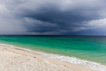 Fototapeta premium Adang Island in Tarutao National Park, South Thailand. Stormy weather, dense clouds, emerald green Andaman sea, white sand beach, dramatic view.