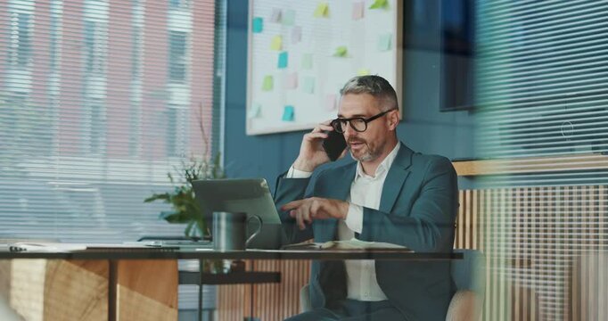 Laptop, businessman and phone call in office for financial development, investment and deal. Manager, offer or investor talking on mobile communication for finance, funding or budget negotiation