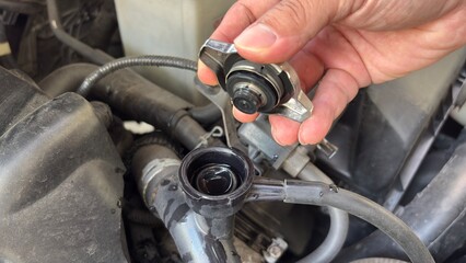 Hand of car auto mechanic engine, technician service check coolant cooling fluid water, he open radiator cap for change or repair the in garage. Check car radiator, car maintenance 