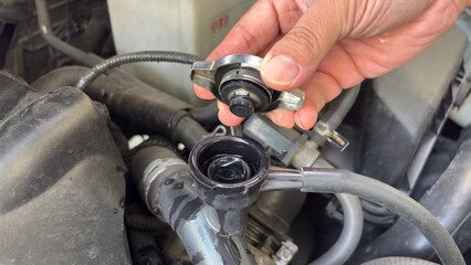 Fototapeta premium Hand of car auto mechanic engine, technician service check coolant cooling fluid water, he open radiator cap for change or repair the in garage. Check car radiator, car maintenance 