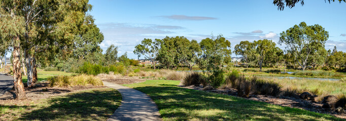 Curved pedestrian footpath through native parkland and wetlands in Manor Lakes, Melbourne, Australia—a sustainable suburban design and community-oriented green space. © Doublelee