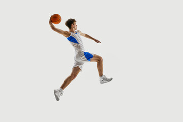 Final goal. Energetic basketball leap captured in peak motion, athlete extending hand ready for throw against white background. Concept of sport, competition, active and healthy lifestyle, game