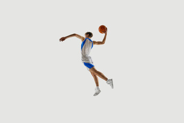 Back view photo. Athlete leaping high for slam dunk, arm extended behind with confident motion against white background. Concept of sport championship, tournament, game, training. Ad