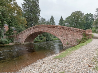 A scenic view of Pooley Bridge spanning a tranquil river in picturesque surroundings