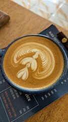 Golden flat white coffee with latte art on menu and wooden table at local cafe