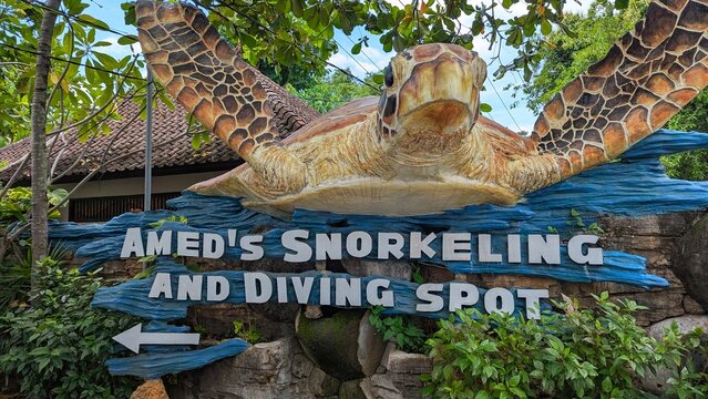 Giant sea turtle statue and Amed's snorkeling and diving spot sign in Bali Indonesia