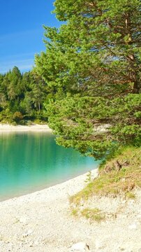Quiet alpine lake Urisee with turquoise water and natural shoreline in Tirol, peaceful forest and mountain landscape backdrop