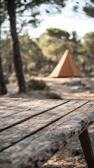 Rustic wooden picnic table in a serene forest setting with a tent in the background creating a peaceful camping atmosphere for outdoor adventure and relaxation