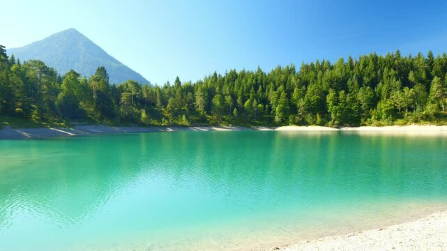 Mountain lake Urisee with crystal blue water and forest-covered hills near Reutte in Tirol, summer calm and pure atmosphere