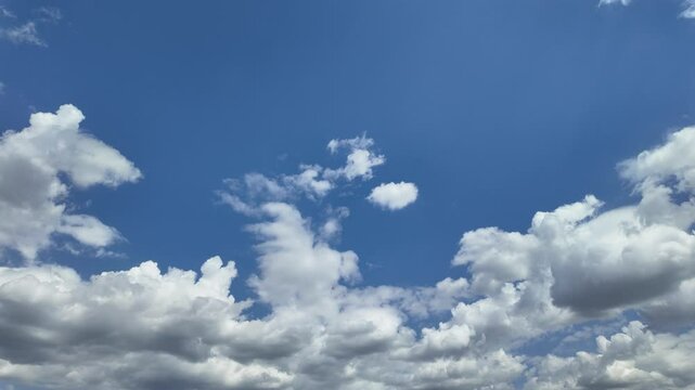 Timelapse of soft white clouds moving clear blue sky